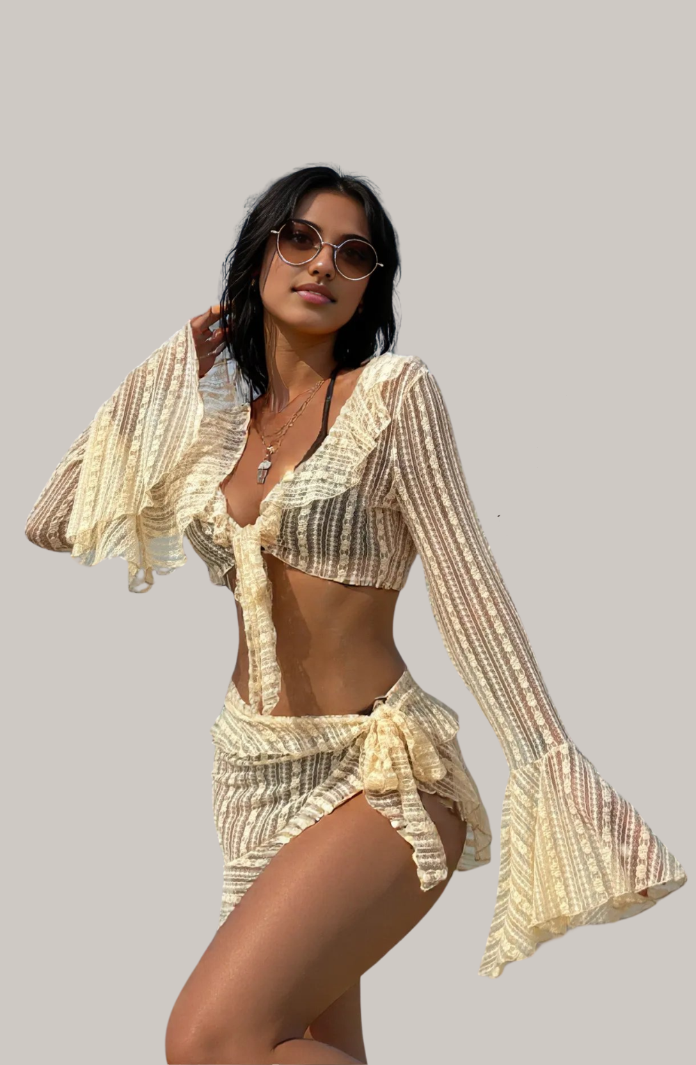 A woman wearing a beige lace bikini set with long bell sleeves and a matching wrap skirt.